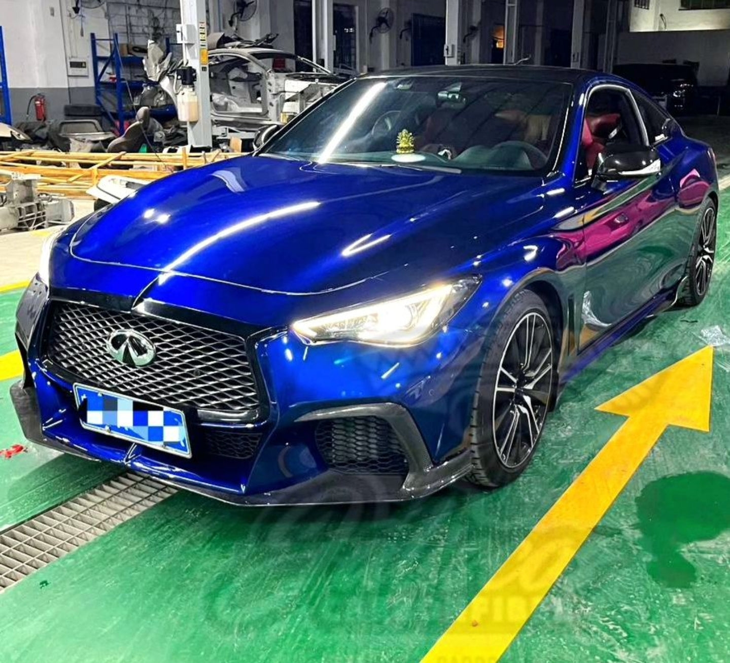 Blue Infiniti Q60 equipped with the JCF Carbon Fiber Front Bumper in a workshop.
