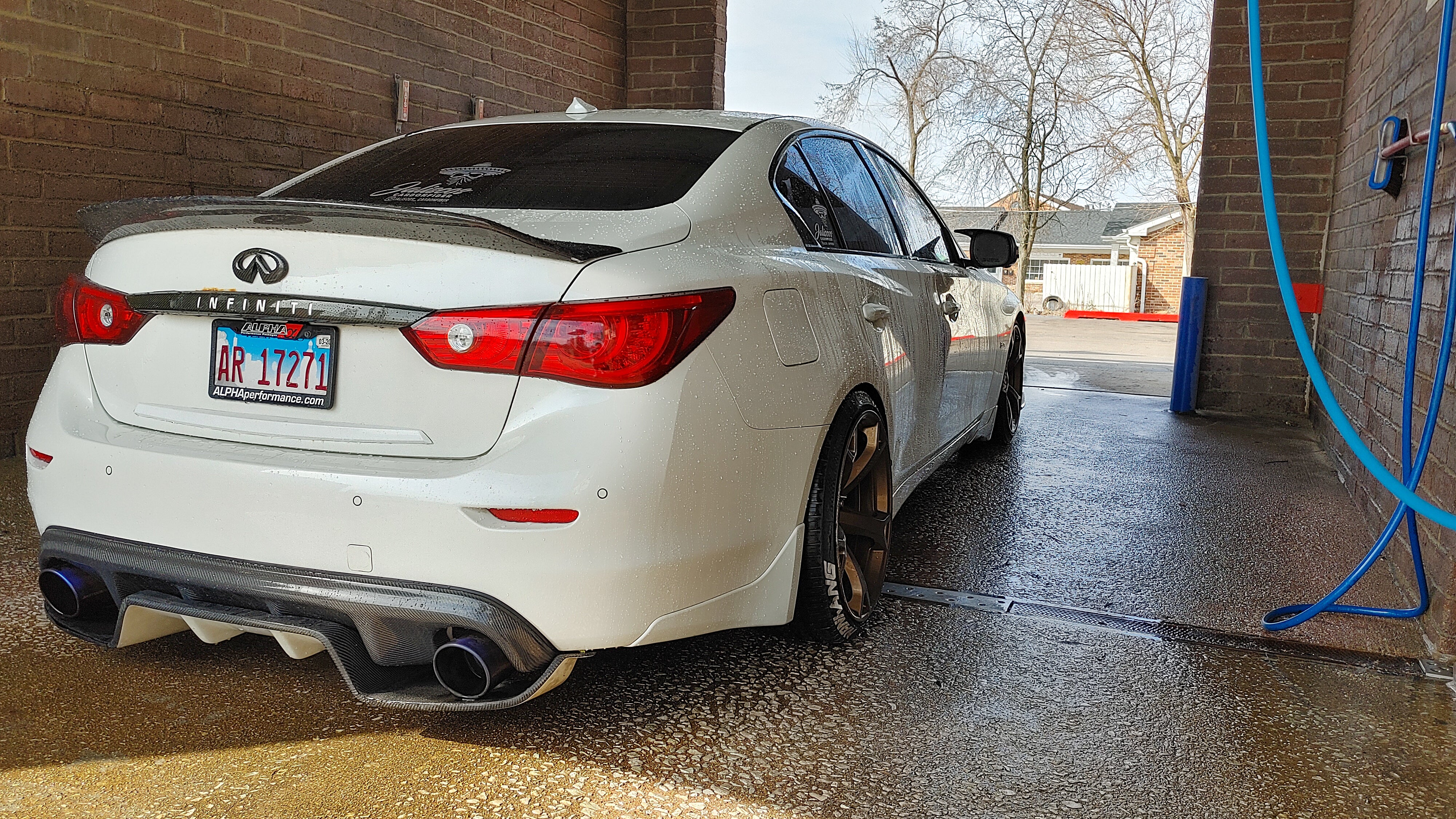 White Q50 sedan being washed, highlighting Jalisco's carbon fiber diffuser.