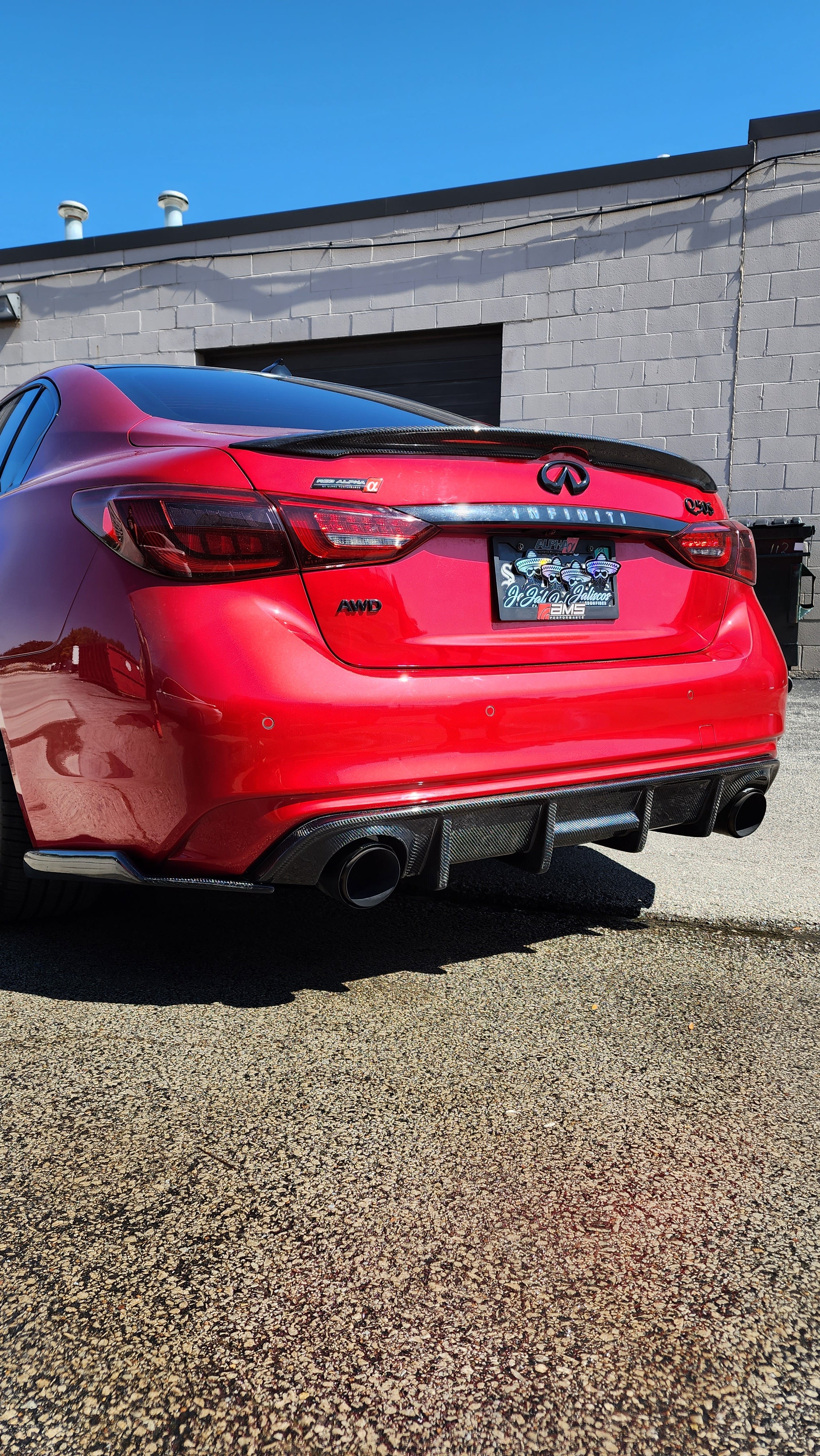 Red Infiniti Q50 2018 showcasing Jalisco's CF Carbon Fiber 'OG' Style Diffuser, captured in a wider angle." Red Q50 2018 with