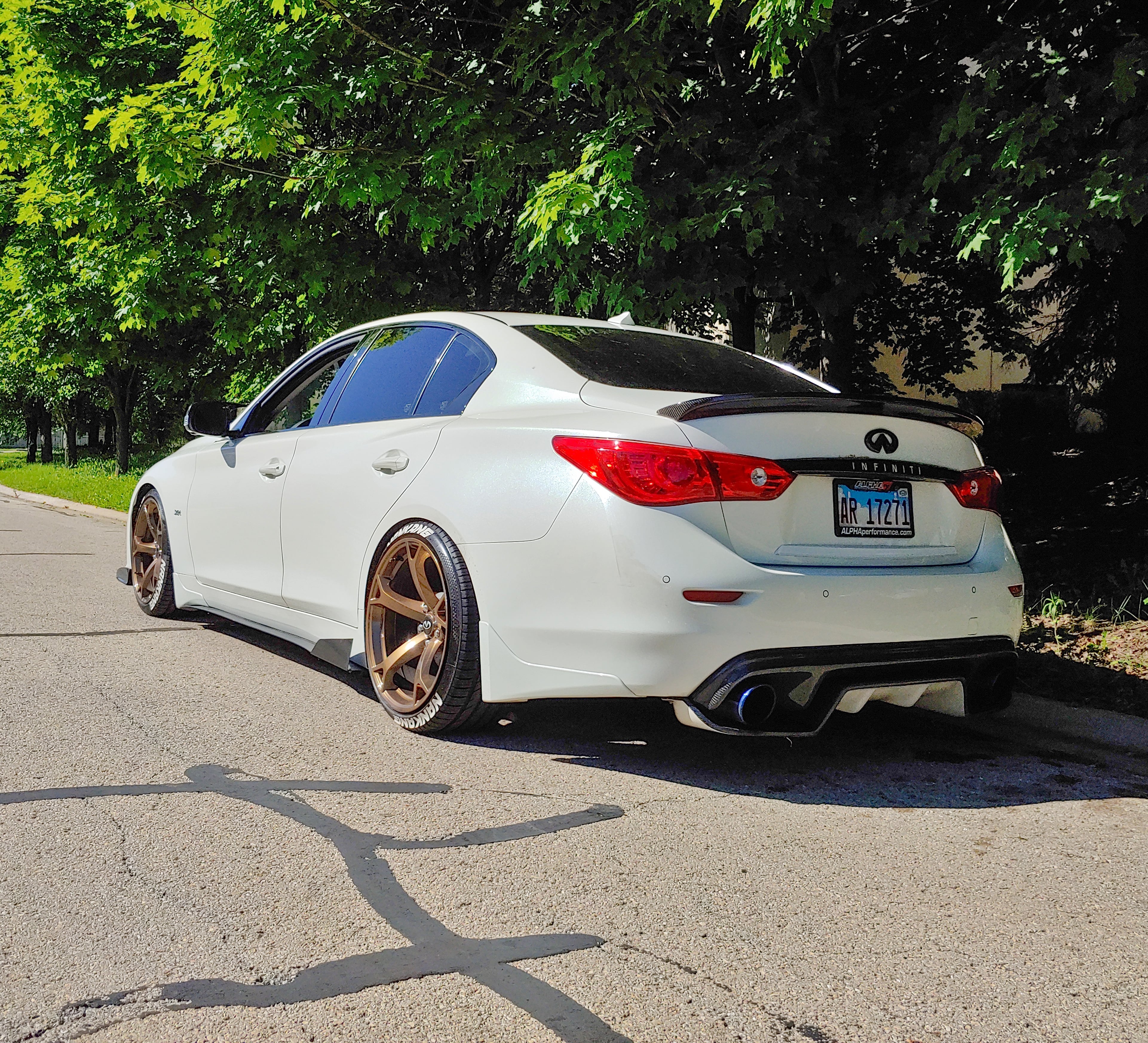White Q50 sedan in a forest setting, equipped with Jalisco's carbon fiber diffuser.
