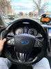 Load image into Gallery viewer, Jalisco&#39;s CarbonFiber Steering Wheel with suede-like grips, blue stitching, a dark blue stripe, accompanied by a custom airbag cover showcasing a blue Infiniti logo for Infiniti Q50 2014-2017