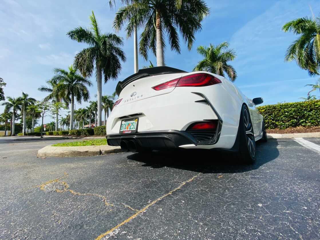 Infiniti Q60 in white with Jalisco's C Blades, parked outdoor showing full rear profile.